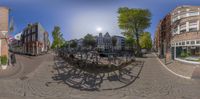 there are some bicycles parked in the center of this street area under the sun and clouds