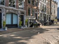 a brick street with two bicycles parked on either side of it and a tall building in the distance