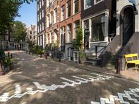 a bicycle lane and street lined with houses in the area where you can sit and watch people cross the road