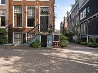 a brick paved area with stairs and a building in the background and some bushes in front of it