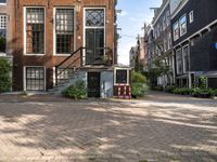 a brick paved area with stairs and a building in the background and some bushes in front of it