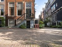 a brick paved area with stairs and a building in the background and some bushes in front of it