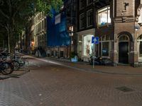 two bikes parked on the sidewalk next to some building by street lamps at night at night