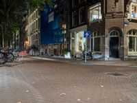 two bikes parked on the sidewalk next to some building by street lamps at night at night