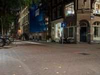 two bikes parked on the sidewalk next to some building by street lamps at night at night