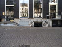 a very small apartment building with large windows and stone pathway outside a door on the street