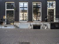 a very small apartment building with large windows and stone pathway outside a door on the street