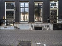 a very small apartment building with large windows and stone pathway outside a door on the street