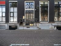 a very small apartment building with large windows and stone pathway outside a door on the street