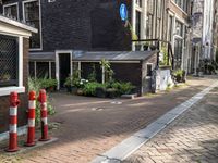 street with lots of buildings and potted plants in the middle of it next to an older brick building