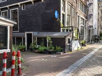 street with lots of buildings and potted plants in the middle of it next to an older brick building