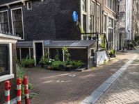 street with lots of buildings and potted plants in the middle of it next to an older brick building