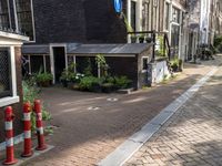 street with lots of buildings and potted plants in the middle of it next to an older brick building