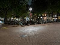 a street corner with bikes parked on the curb in front of them at night time