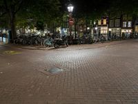 a street corner with bikes parked on the curb in front of them at night time