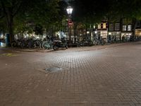 a street corner with bikes parked on the curb in front of them at night time