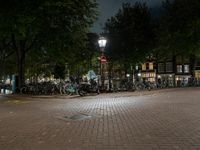 a street corner with bikes parked on the curb in front of them at night time