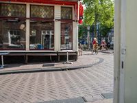 a bike rider rides down the street past buildings on either side of a cobblestone street