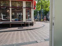 a bike rider rides down the street past buildings on either side of a cobblestone street