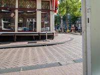 a bike rider rides down the street past buildings on either side of a cobblestone street