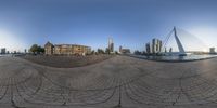 a fish eye lens captures an urban scene and riverbanks, looking up at the city and buildings