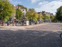 bicycles parked at a cobblestone road in a city street with many buildings behind them