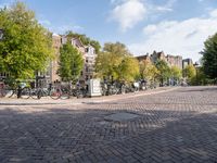 bicycles parked at a cobblestone road in a city street with many buildings behind them