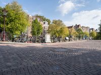 bicycles parked at a cobblestone road in a city street with many buildings behind them