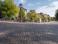 bicycles parked at a cobblestone road in a city street with many buildings behind them