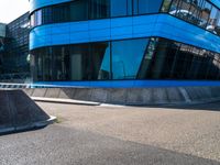 a skate park that is near a blue building with windows on it and skateboard ramps in the foreground