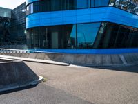 a skate park that is near a blue building with windows on it and skateboard ramps in the foreground