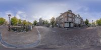 an intersection with old fashioned buildings and bicycles on the sidewalk in a town square, seen from a fish eye lens