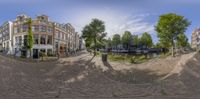 a panorama of a street in an old european city center with lots of trees and brick walkways