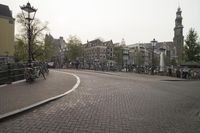 a paved street with a lot of bicycles and buildings in the background and a couple people outside