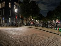 bicycles and buildings on the street at night in a town of amsterdam, with traffic