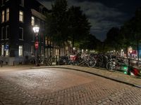 bicycles and buildings on the street at night in a town of amsterdam, with traffic