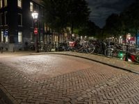 bicycles and buildings on the street at night in a town of amsterdam, with traffic