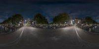 a fish - eye lens photo taken at night with a few people sitting down by the water