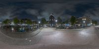 a city at night with a small plaza and buildings at the end of it, as seen in fish eye lens