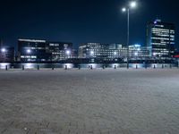 an empty brick pathway beside the water at night with lights shining on it's sides