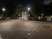 night scene of city block with cobblestone pathway and multiple light posts and lights