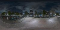 the image shows people walking on a street at night time in a panorama of an urban area