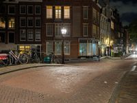 a street with a light that is shining on the street and people on a bench