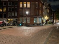 a street with a light that is shining on the street and people on a bench