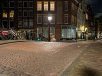 a street with a light that is shining on the street and people on a bench