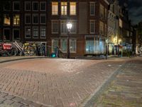 a street with a light that is shining on the street and people on a bench