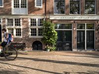 the girl is riding her bicycle in front of the building with the large windows of the old town house