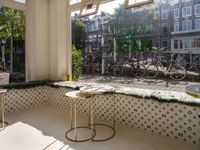 the front of a large green and white shopfront with bicycles and a table and chair