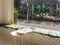 the front of a large green and white shopfront with bicycles and a table and chair