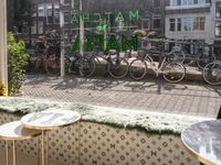 the front of a large green and white shopfront with bicycles and a table and chair